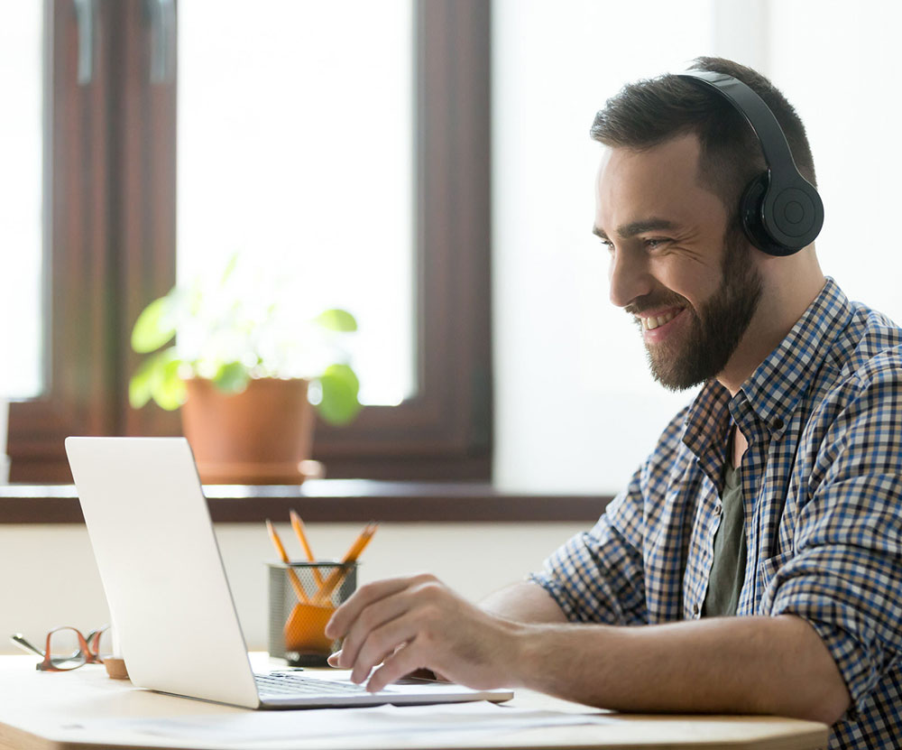 Man wearing headphones and using a laptop for a Zoom Webinar